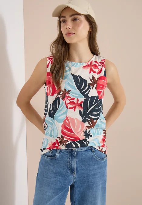 Top mit Rundhals und Blätterprint light alabaster white Frau trägt ärmelloses Top mit großem Blumenmuster in leuchtenden Farben und Jeanshose.