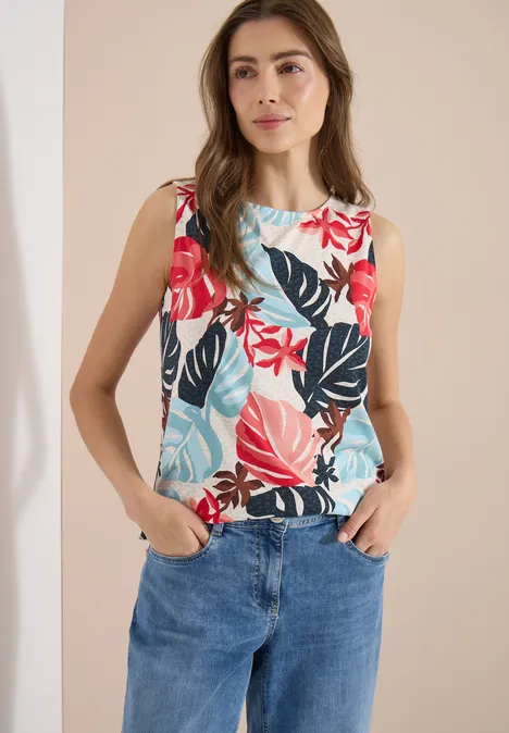 Top mit Rundhals und Blätterprint light alabaster white Frau in Jeans und ärmelloser Bluse mit buntem Blatt-Print steht vor neutralem Hintergrund.
