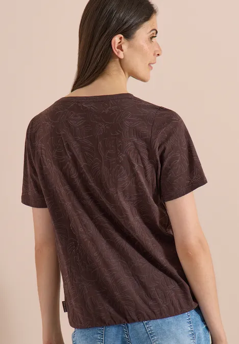 T-Shirt in Ausbrenner-Optik brown cacao Eine Frau von hinten in einem braunen T-Shirt mit kurzem Arm vor beigem Hintergrund.