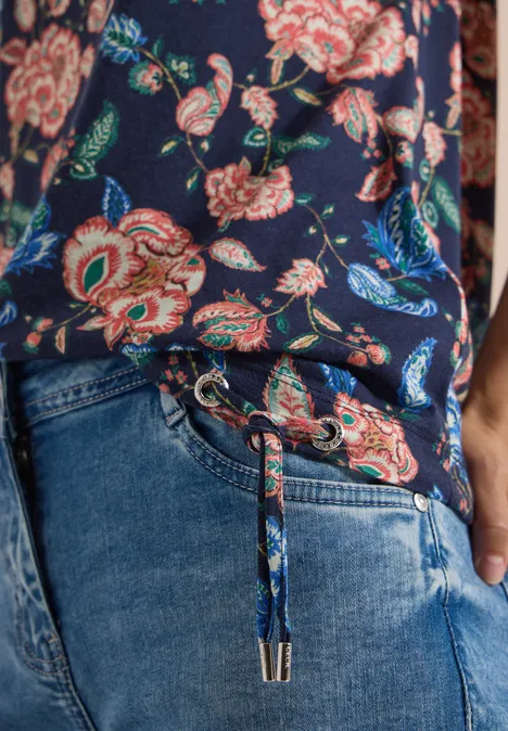Kurzarm Shirt mit Boatneck und Raffung urban dark blue Eine Person trägt ein blaues, geblümtes Oberteil und Jeans mit Tunnelzug, Hand in der Tasche.