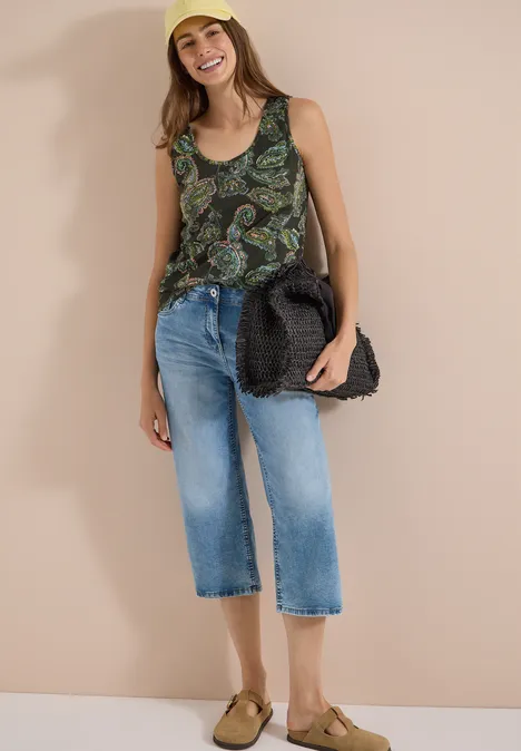 Top mit gerundetem V-Neck und Flechtdetail raw khaki Frau mit unkenntlichem Gesicht in gemustertem Top, Cropped-Jeans und Sandalen mit Strohtasche.