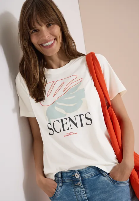 T-Shirt mit Rundhals und Frontprint vanilla white Frau mit roter Tasche trägt weißes T-Shirt 'SCENTS' und Jeans vor hellem Hintergrund.