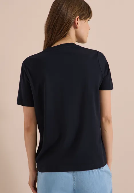 T-Shirt mit Rundhals und Frontprint universal blue Frau von hinten in schlichten schwarzem T-Shirt und hellblauen Jeans.