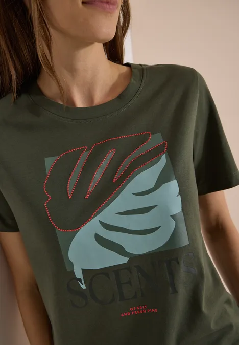 T-Shirt mit Rundhals und Frontprint khaki Frau trägt olivgrünes T-Shirt mit abstraktem zweifarbigen Blatt und Schriftzug 'SCENT'.