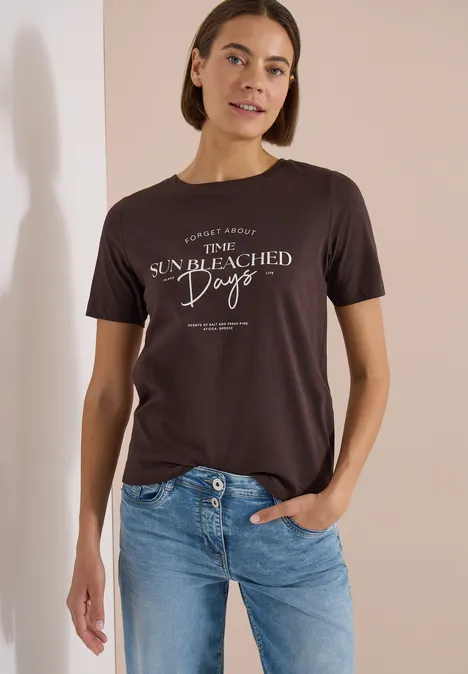 T-Shirt mit Boat Neck und Wording Artwork brown cacao Eine Person trägt ein dunkelgraues T-Shirt mit weißem Schriftzug 'The sun bleached days' und blaue Jeans.