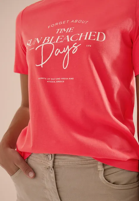 T-Shirt mit Boat Neck und Wording Artwork coral Rotes T-Shirt mit weißem Schriftzug "Forget about time unbleached days" und beiger Hose.