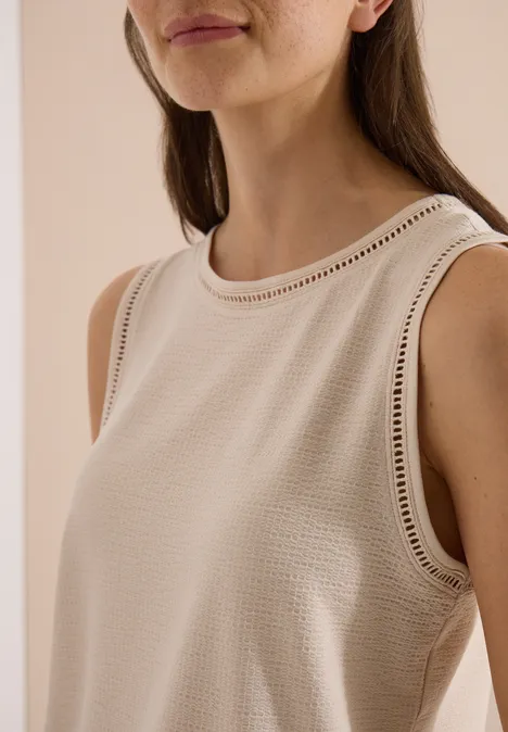 Top met boothals en kanten details pearl beige Nahaufnahme einer Frau in ärmellosem, beigem Top mit filigraner Lochstickerei.