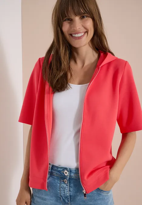 Kapuzenjacke mit seitlichen Tunnelzügen coral Person trägt korallenrote kurzärmelige Kapuzenjacke, weißes Top und Jeans.