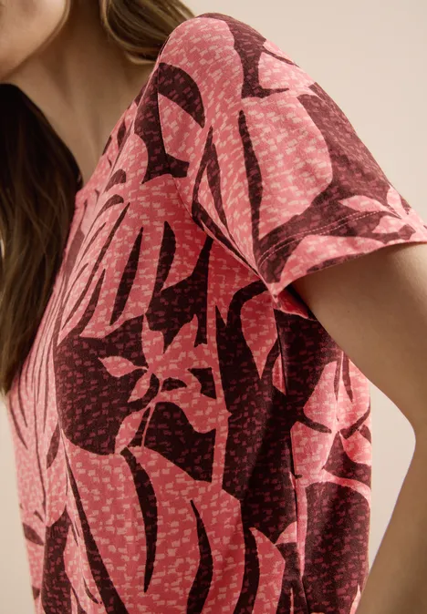 T-Shirt mit Rundhals und Blätterprint coral Nahaufnahme einer pinken Bluse mit schwarzem, großem Blattmuster und Punkten.