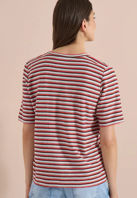 T-Shirt mit Struktur und Streifen brown cacao Frau von hinten, trägt gestreiftes T-Shirt mit roten, weißen und blauen Streifen vor beigem Hintergrund.