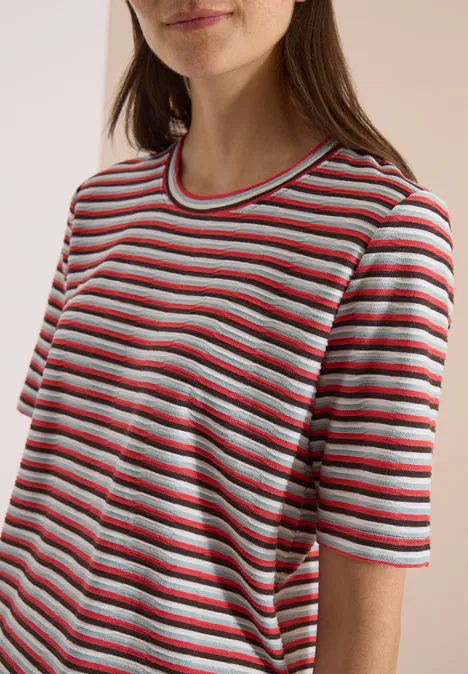 T-Shirt mit Struktur und Streifen brown cacao Halbporträt einer Frau mit rot-grau-weiß gestreiftem T-Shirt und locker fallenden braunen Haaren.