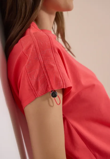 Rotes T-Shirt mit Kabel und Stecker am Ärmel, sitzende Person im Profil