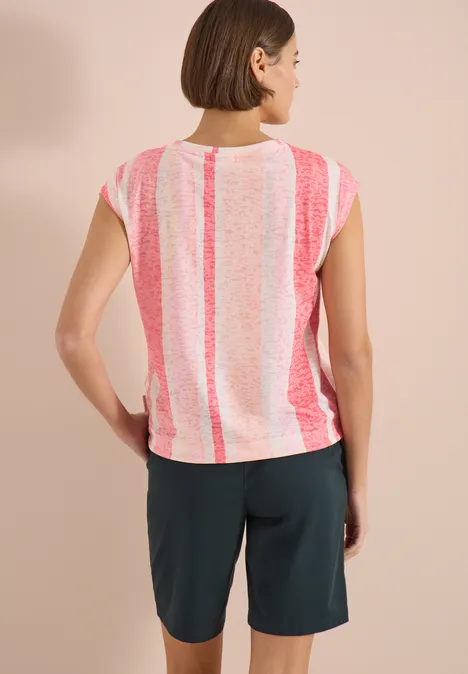 Rückenansicht einer Frau in rosa-weiß gestreiftem T-Shirt und dunklen Shorts vor neutralem Hintergrund.