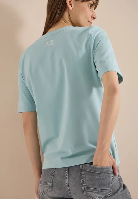 T-Shirt mit Rundhals und Brusttasche crystal mint Person von hinten mit hellblauem T-Shirt und grauen Jeans vor neutralem Hintergrund.