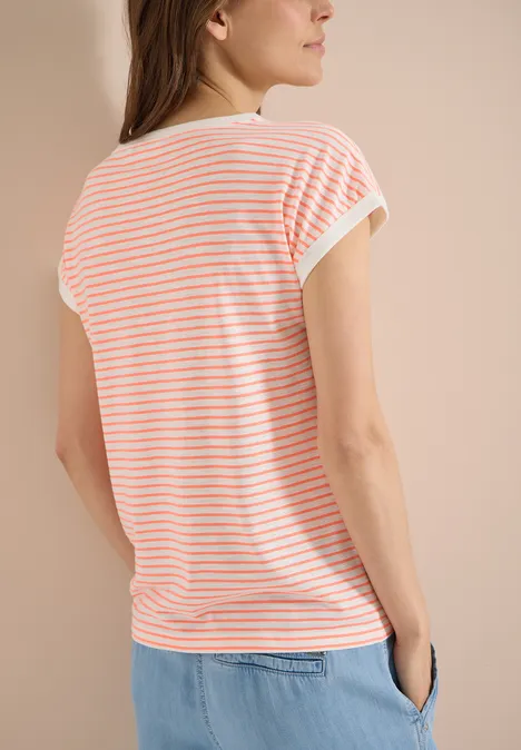 T-Shirt mit Boat Neck und Streifen coral Frau von hinten in gestreiftem Shirt und blauer Hose vor neutralem Hintergrund.