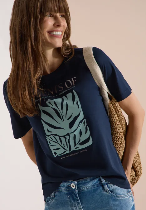 T-Shirt mit Rundhals und Frontprint universal blue Frau trägt dunkelblaues T-Shirt mit grünem Blatt-Print, Jeans und geflochtene Umhängetasche.