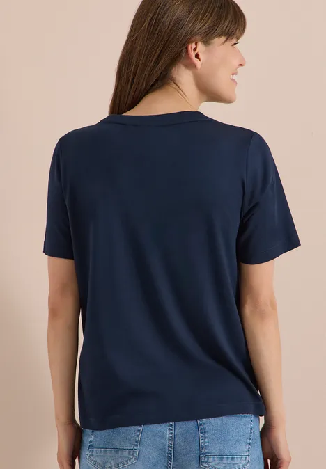 T-Shirt mit Rundhals und Frontprint universal blue Eine Frau von hinten trägt ein schlichtes, dunkelblaues T-Shirt und Jeans.