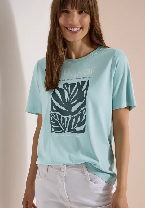 T-Shirt mit Rundhals und Frontprint crystal mint eine Frau trägt ein hellblaues T-Shirt mit Zebramuster und weiße Hose, Gesicht unscharf.