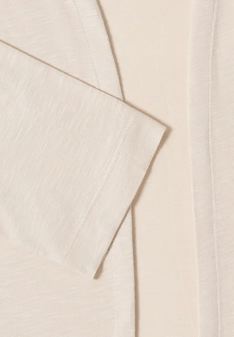 Close-up van een crèmekleurig, gestructureerd colbert met strakke lijnen en zachte uitstraling.