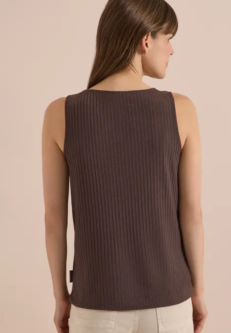 Achteraanzicht van een vrouw met lang haar, die een bruine, geribde mouwloze top draagt tegen een lichte achtergrond.