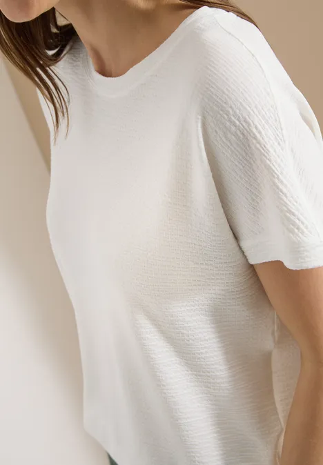 Weißes geripptes Kurzarm-T-Shirt an einer Frau, Seitenansicht.