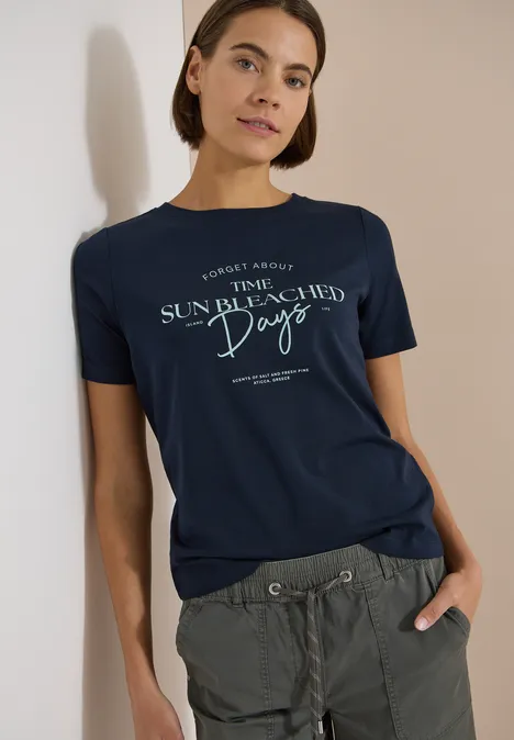 T-Shirt mit Boat Neck und Wording Artwork universal blue Person trägt dunkelblaues T-Shirt mit Aufdruck 'The Sun Bleached Days' und grüne Cargo-Hose.