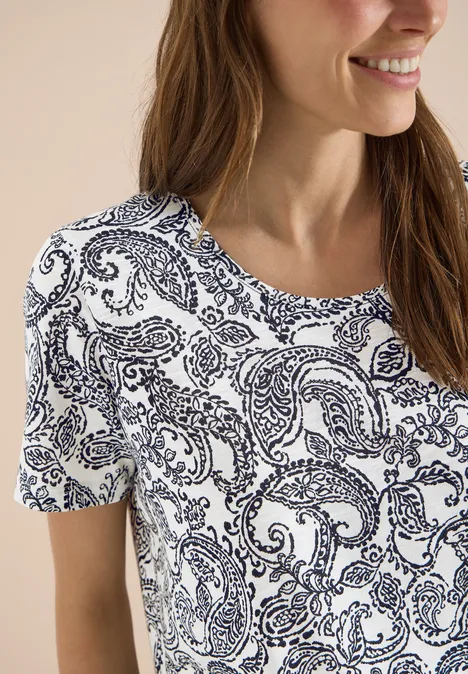 Vrouw in wit T-shirt met donkerblauw paisleymotief, korte mouwen, casual stijl.