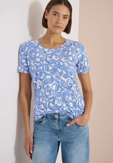 Vrouw draagt blauw-wit paisleyshirt met spijkerbroek.
