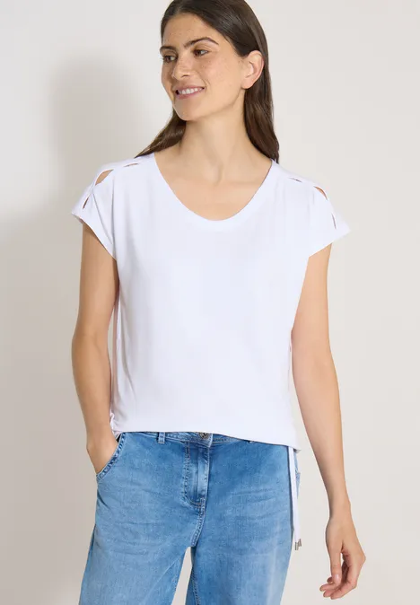 Vrouw in simpel wit t-shirt met opgerolde mouwen en blauwe spijkerbroek.