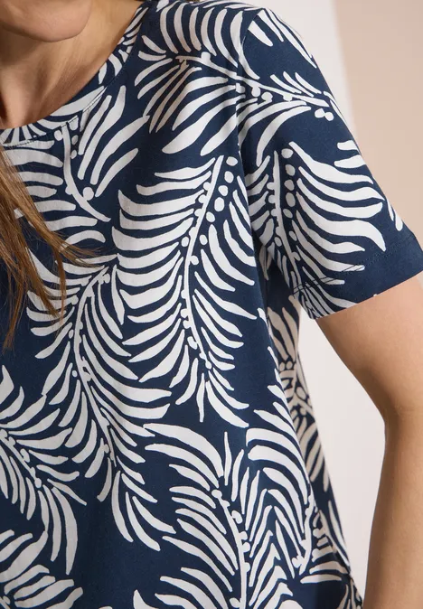 Iemand draagt een donkerblauw T-shirt met wit bladpatroon en korte mouwen.