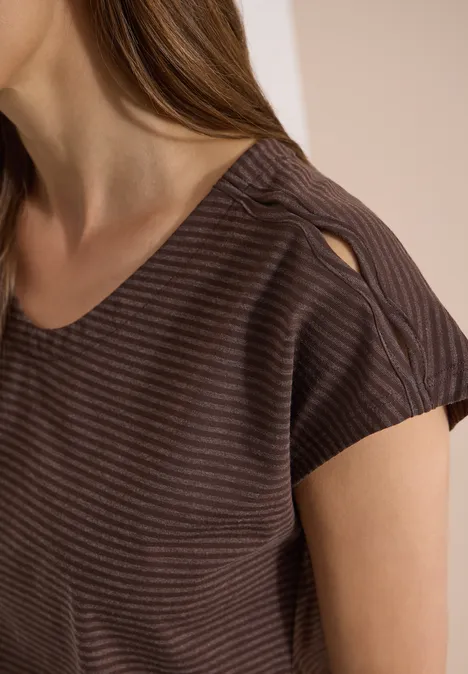Frau in braun gestreiftem Shirt mit Rundhalsausschnitt und Schulter-Aussparung.