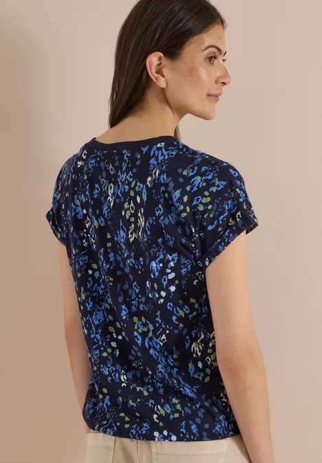 Frau von hinten in kurzärmeligem dunkelblauen Top mit floralem Muster.