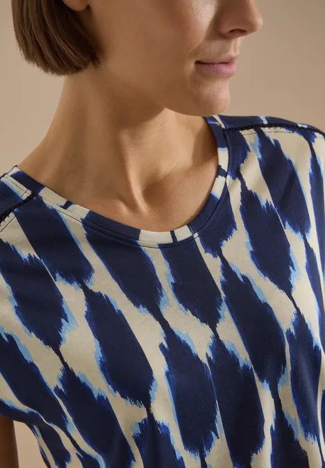 T-Shirt mit V-Neck und Spitzendetail urban dark blue Frau trägt blau-weiß gemustertes Oberteil mit Pinselstrichdesign.