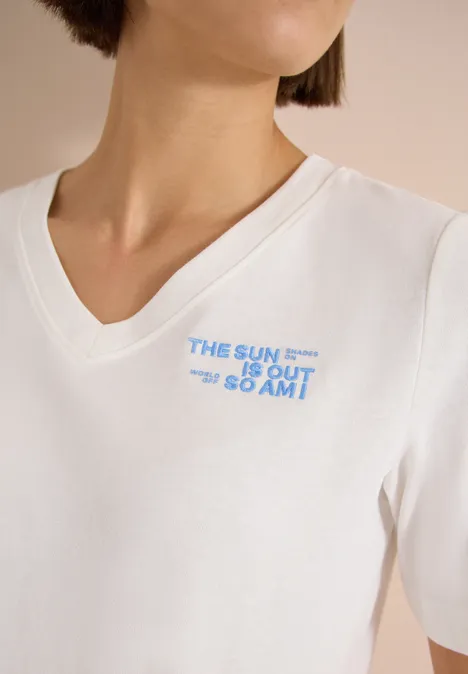 Shirt met V-hals en tekstdetail vanilla white Witte V-hals T-shirt met blauwe tekst 'THE SUN IS OUT GO AMT' op de borst.
