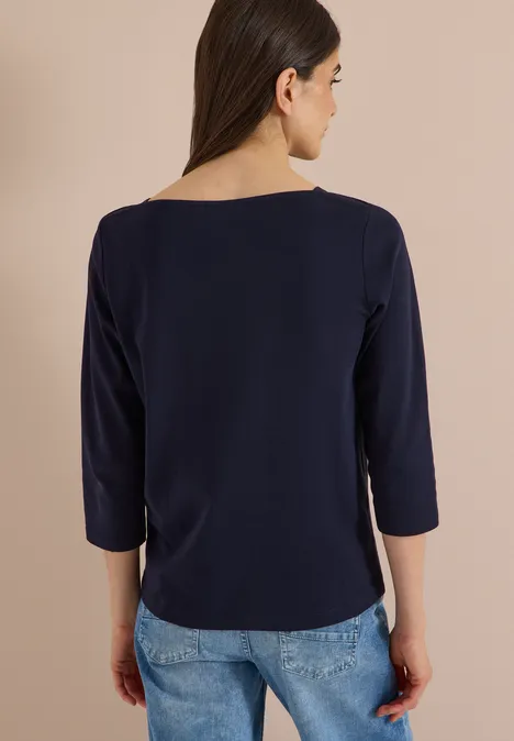 Rückenansicht einer Frau im dunkelblauen 3/4-Shirt und hellblauen Jeans.