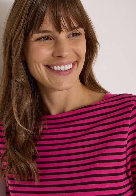 3/4-Arm Shirt mit Boat Neck und Streifen pink flash Eine lächelnde Frau mit braunen Haaren in einem pink-schwarzen gestreiften Shirt.