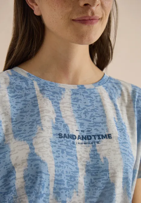 Shirt in uitgebleekte look met tekst urban dark blue Portret van een vrouw in een blauw-wit gestreept T-shirt met tekst 'SAND AND TIME'