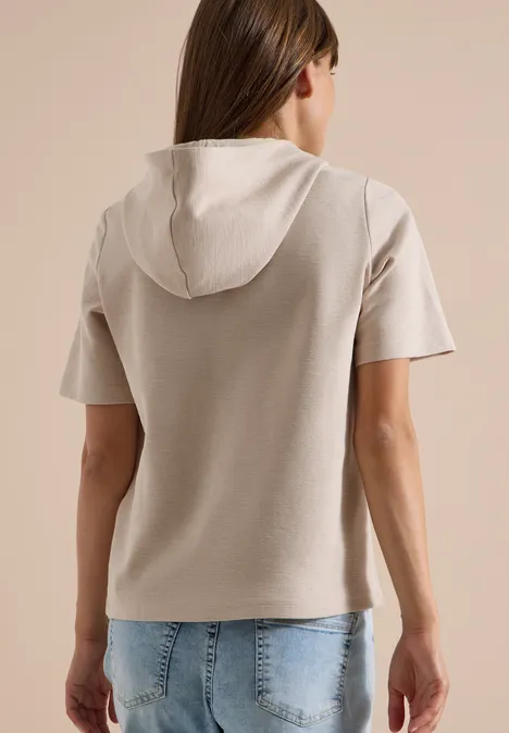 Kurzarm Shirt mit Kapuze und Wording cashmere beige Frau von hinten in beigem Kurzarm-Hoodie mit Kapuze und Jeans