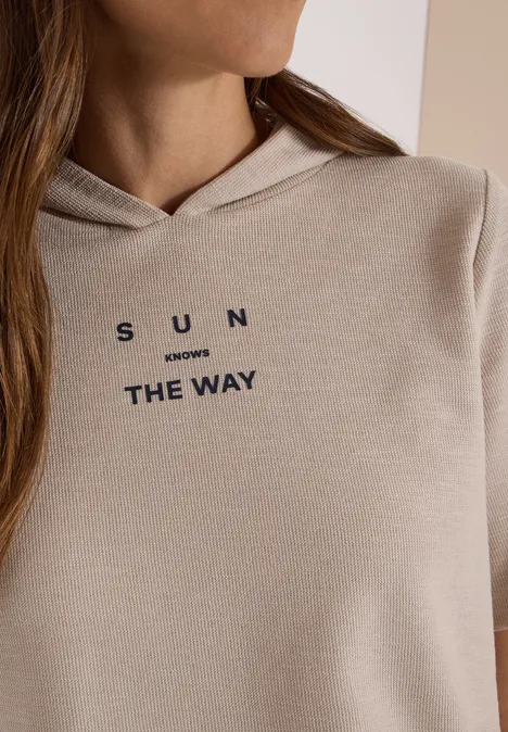 Kurzarm Shirt mit Kapuze und Wording cashmere beige Beige Kapuzenpullover mit dunkler Aufschrift 'SUN inverses THE WAY' an einer seitlich fotografierten Person.