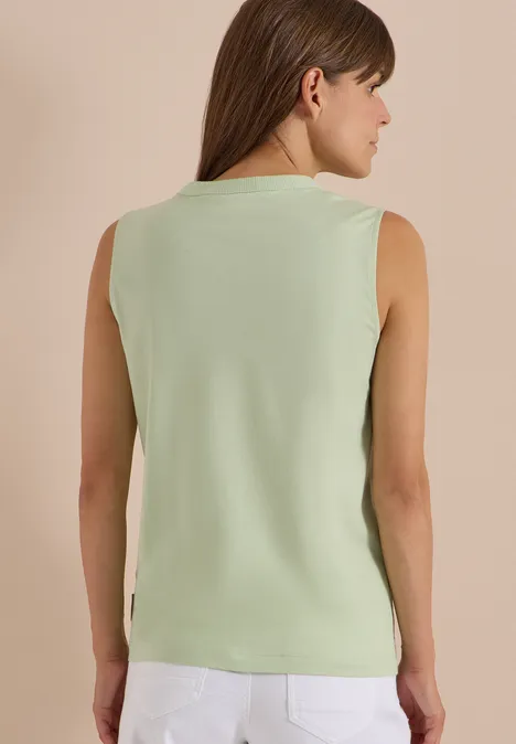 Frau in ärmellosem mintgrünen Top, von hinten fotografiert.