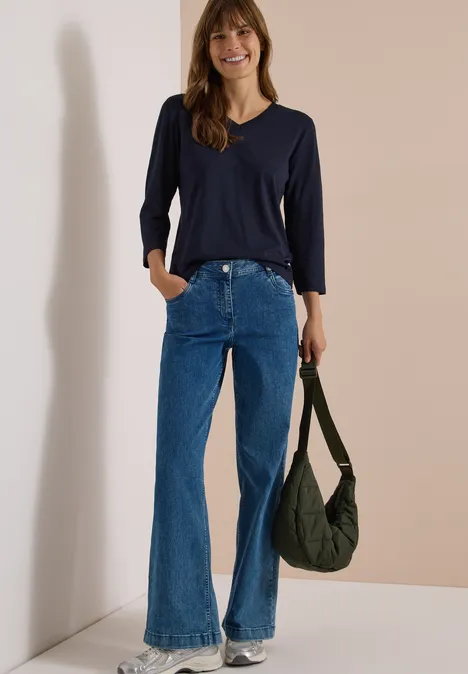 3/4-Arm Shirt in Unifarbe mit V-Neck urban dark blue Frau in dunkelblauem Shirt, Schlagjeans und olivgrünem Beutel vor hellem Hintergrund.