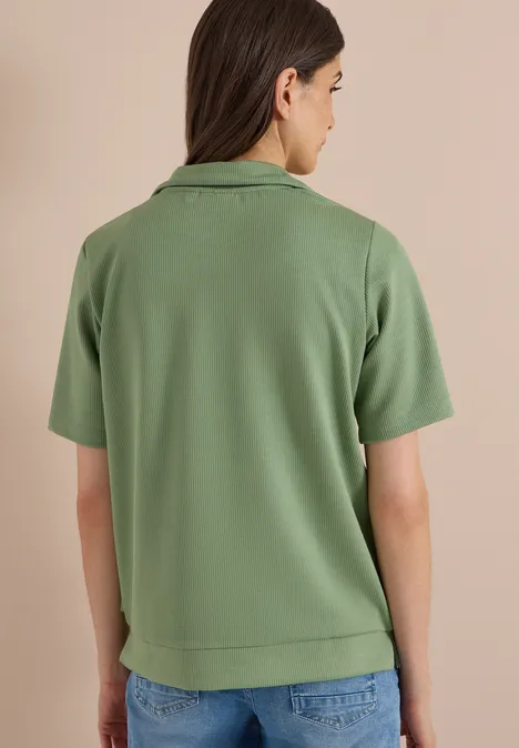 Person von hinten in hellgrünem Polo-Shirt und Jeans