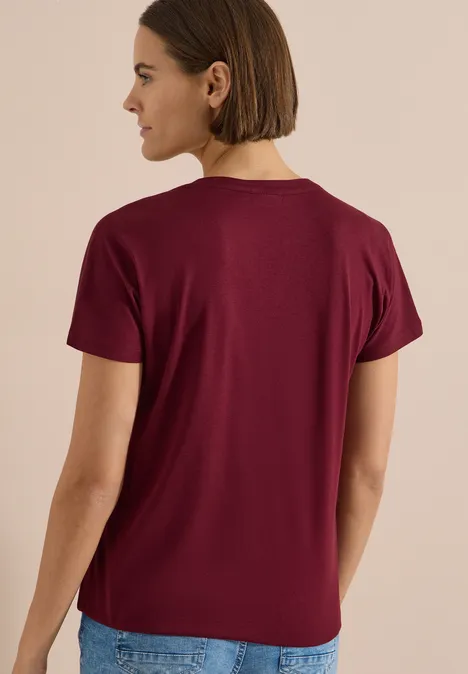 T-Shirt mit Split Neck in Unifarbe red wine Frau von hinten in schlichtem bordeauxfarbenem T-Shirt mit kurzen Ärmeln, Jeans, neutralem Hintergrund.