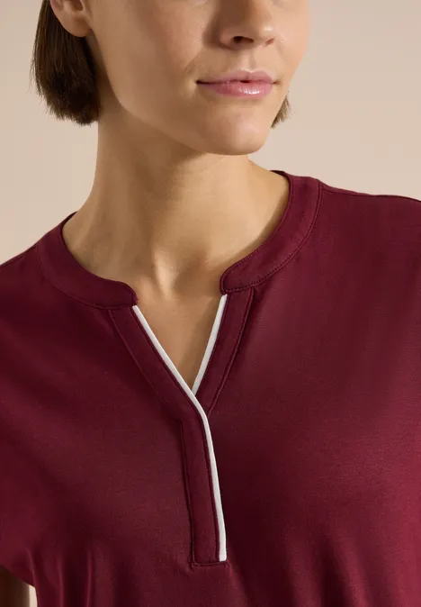 T-Shirt mit Split Neck in Unifarbe red wine Nahaufnahme einer Person in einem burgunderroten Shirt mit V-förmigem Ausschnitt und weißer Ziernaht.