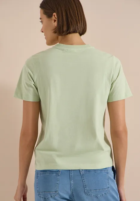 T-Shirt mit Rundhals und Frontprint raw matcha lime Person steht mit dem Rücken zur Kamera, trägt hellgrünes T-Shirt und blaue Jeans.