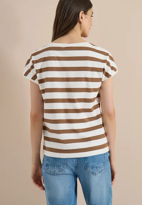 Achteraanzicht van een persoon met een bruin-wit gestreept shirt en blauwe spijkerbroek tegen een beige achtergrond.
