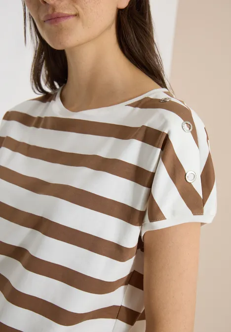 Vrouw met wit T-shirt met bruine strepen en knopen op de korte mouwen.