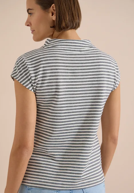 T-shirt à col cheminée et rayures urban dark blue Frau von hinten in gestreiftem T-Shirt vor neutralem Hintergrund.