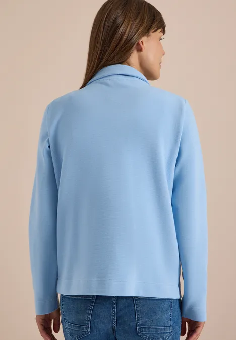 Jas met lange mouwen en ottomanstructuur easy blue Vrouw van achteren met lichtblauwe jas en spijkerbroek tegen neutrale achtergrond.