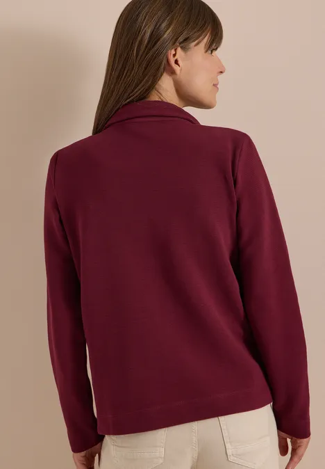 Eine Frau von hinten trägt eine weinrote Fleecejacke.